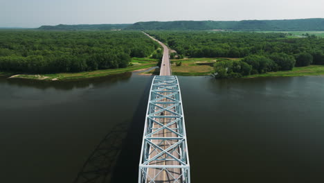 flying over the wabasha-nelson bridge over the mississippi river with lush green forest in the distance