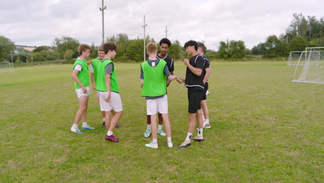 multiracial male soccer players greeting and embracing each other after match on pitch