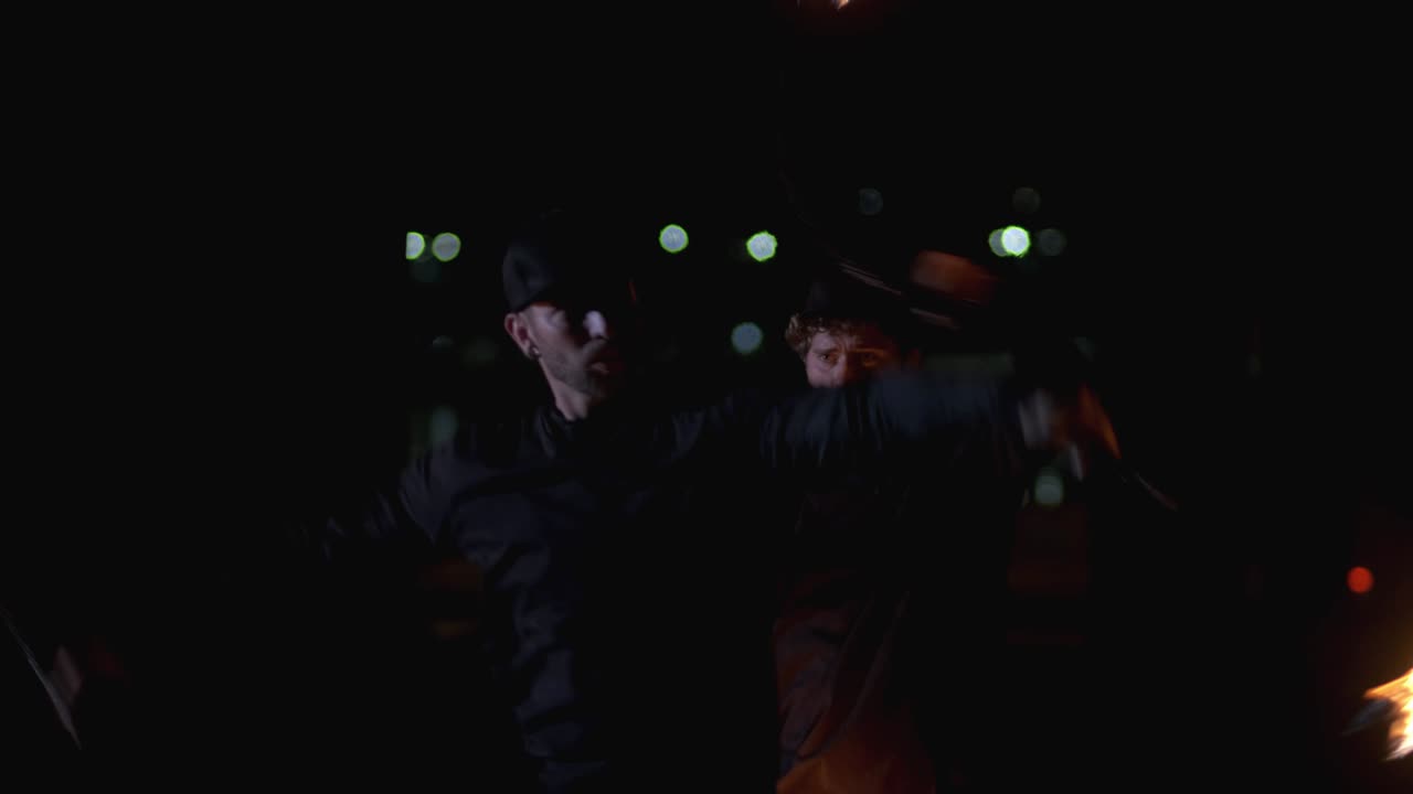 두 명의 화재 쇼 아티스트가 밤에 다리 에서 불공을 회전시니다. 배경에 보케. 밤 공연