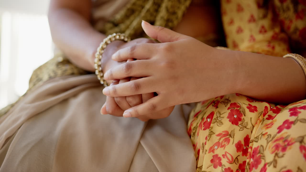 Holding hands, two indian mother and daughter in traditional Indian sari showing support and care