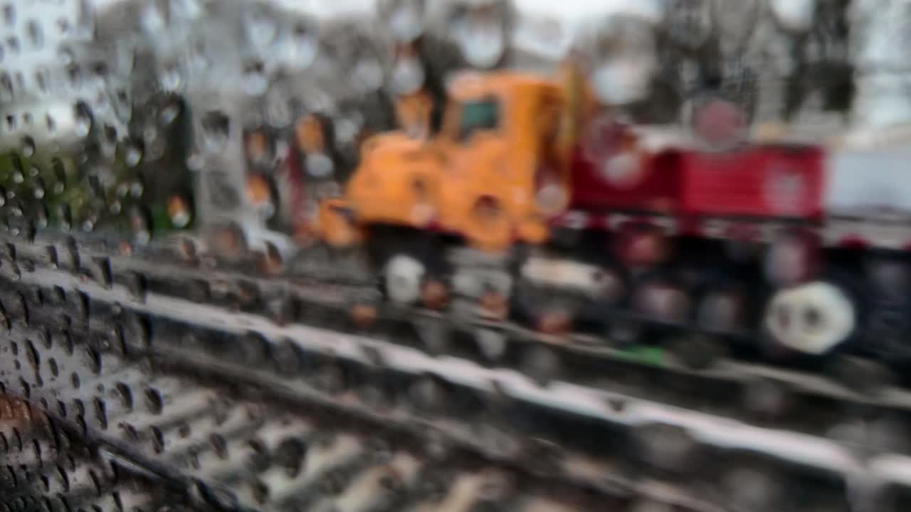 A view from a train passing workers on the railroad tracks on a rainy day