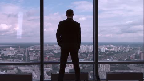 businessman looking out over cityscape from high-rise