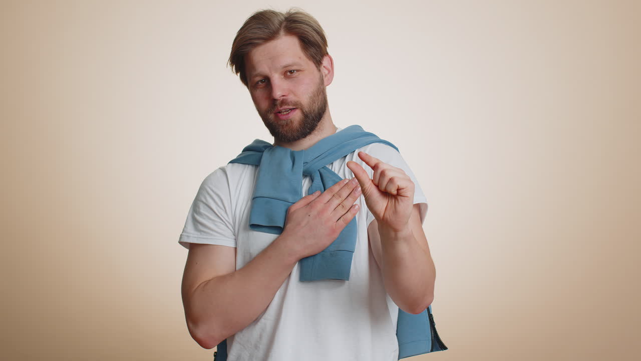 젊은 남자는 회의적인 미소로 약간의 몸짓을 보여주고 작은 크기를 측정하는 최소한의 표시를 보여줍니다.