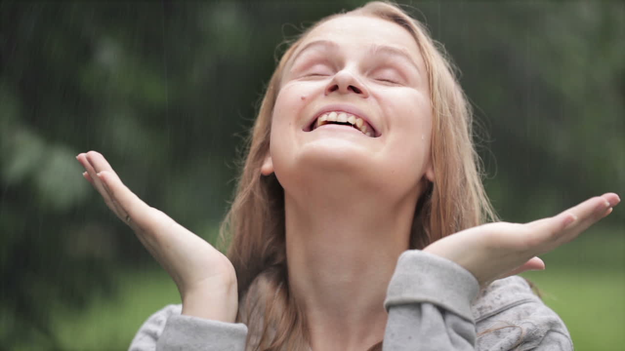 chica disfrutando de la lluvia en el parque