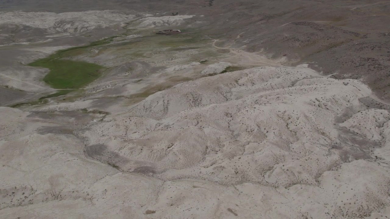 Drone footage of the Moon Landscape badlands with pale clay hills and sparse vegetation near Kosh-Agach, Altai Republic, Russia, remote arid steppe terrain