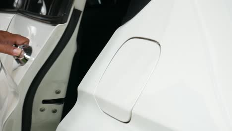 cerrar la mano del hombre abriendo la puerta trasera del coche blanco