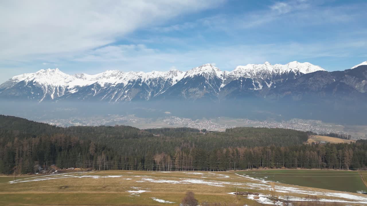 vista aérea por drones de campos de hierba marrón con pequeñas partes cubiertas de nieve y una carretera con bosques y casas