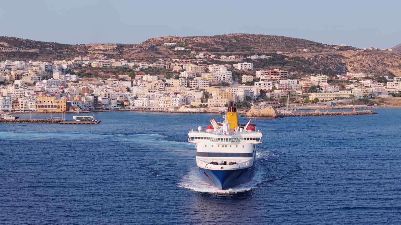 Aerial view of a ferry boat just departing from the port of Karpathos island in Greece. Clear blue waters, island harbor, and maritime atmosphere