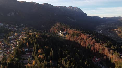 Vista-Aérea-Otoñal-De-Sinaia-Y-El-Castillo-De-Peles-En-Rumania,-Rodeado-De-Un-Colorido-Bosque