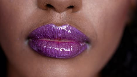 primer plano de lápiz labial de brillo púrpura en los labios de la mujer