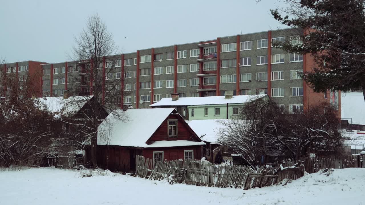 tradicional cabaña de madera del báltico y un edificio residencial soviético en la nieve