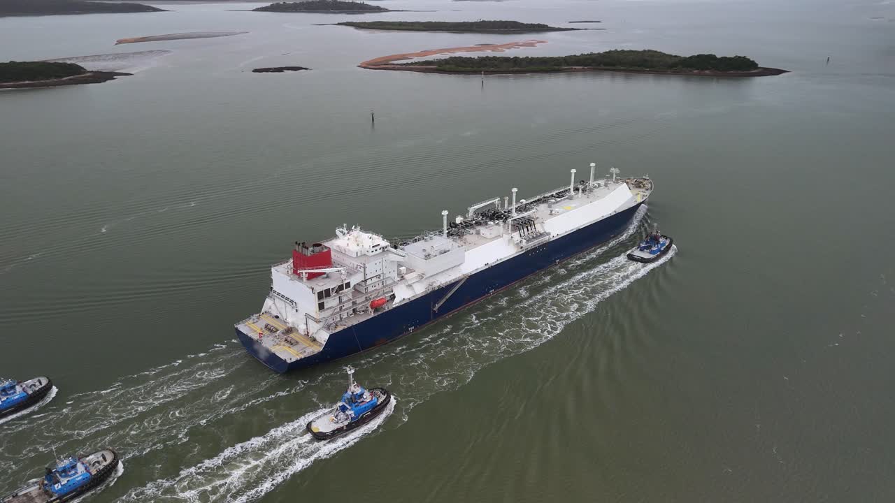 Tug boats accompany freight ship as it leaves commercial ocean port
