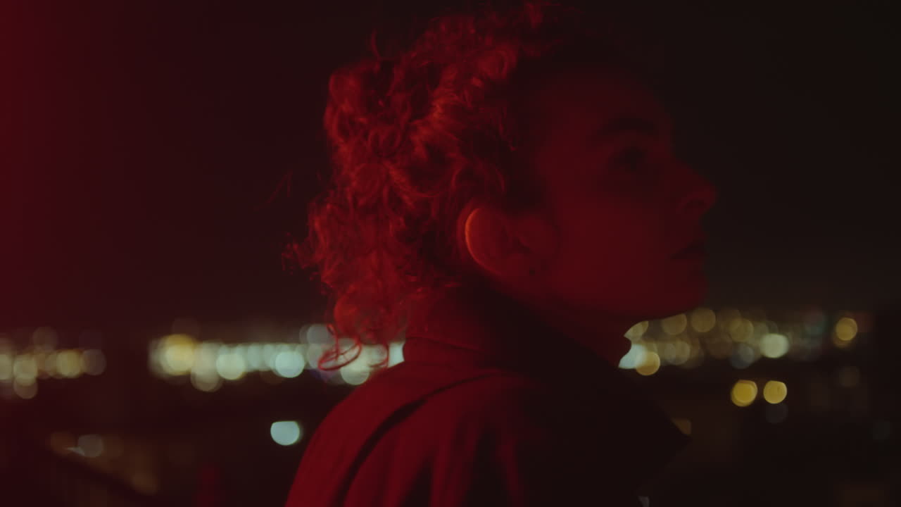Woman Standing in Red Neon Light on Dark Street