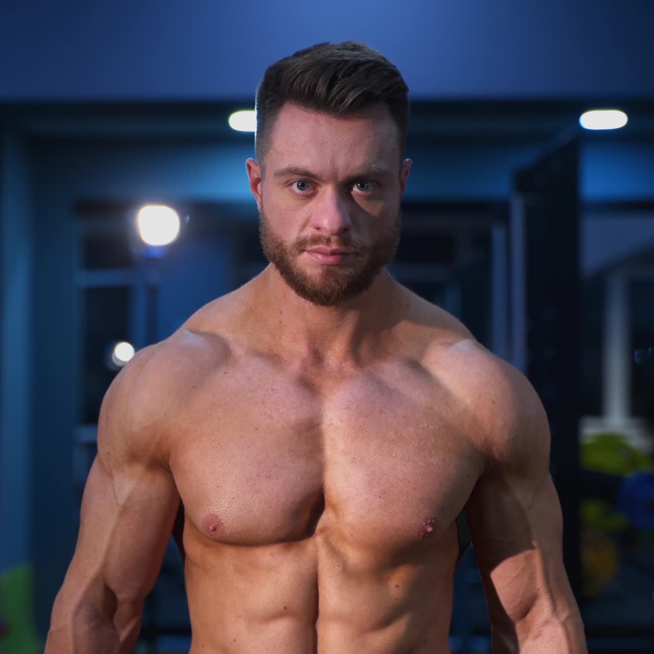 Portrait of shirtless bodybuilder indoors. Power athletic man training bicep muscles in sports centre. Handsome athlete with muscular body in gym
