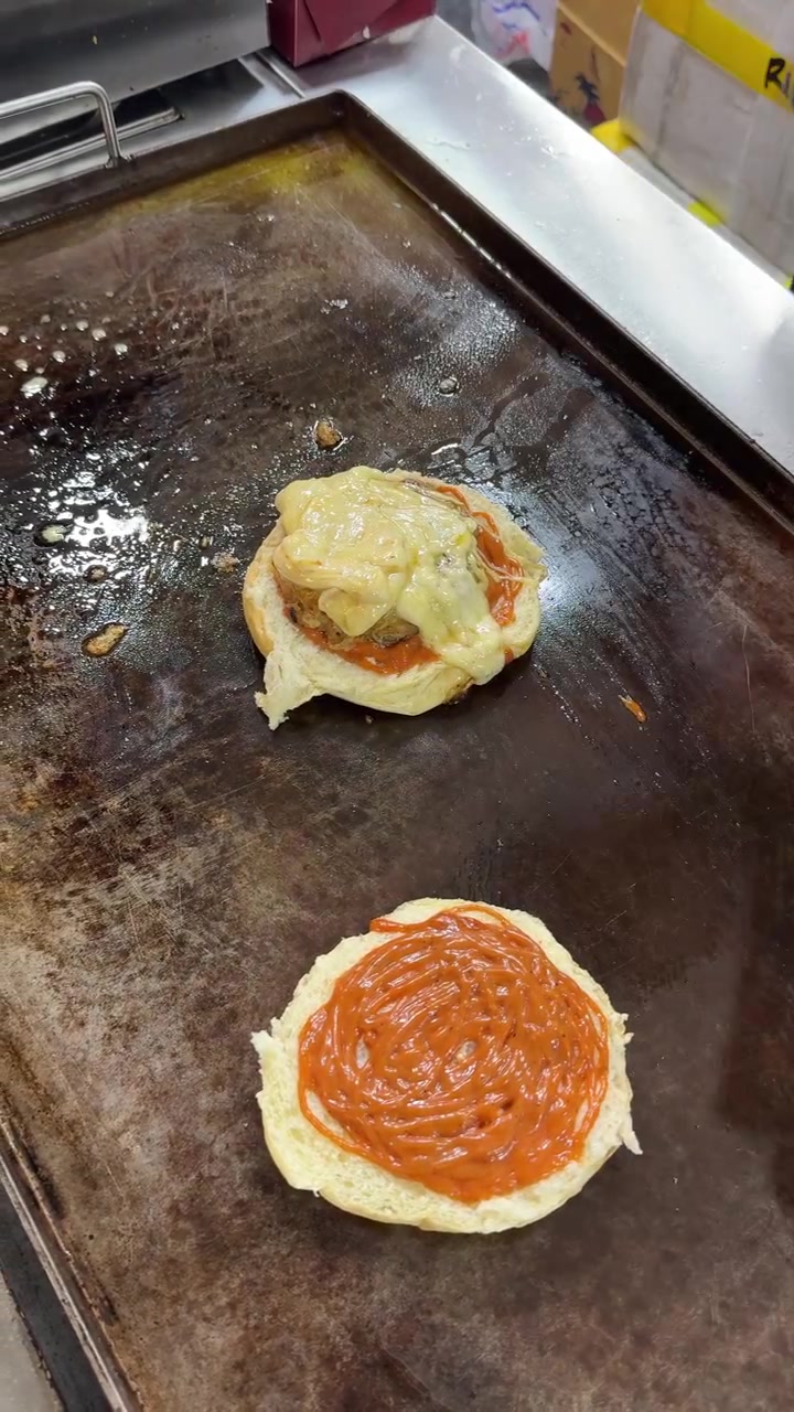 Kokk tilbereder en cheeseburger på en kommersiell stekeplate
