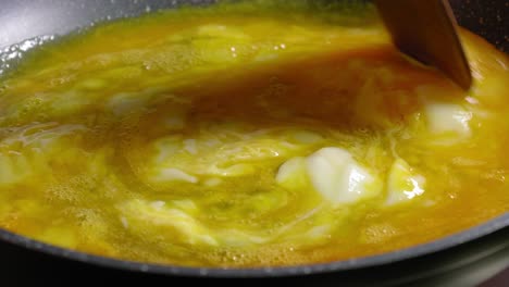 vista cercana de la persona que cocina huevos revueltos en una sartén caliente