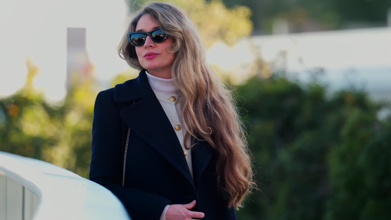 Blonde woman wearing sunglasses looking around outside on a blurred background