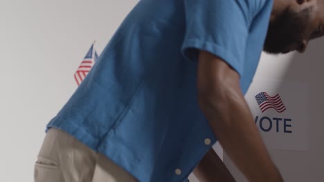 close up of man next to booth with ballot paper in american election deciding how to cast his vote 3