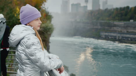 a girl of 10 years old stands at niagara falls, admiring the beautiful view. travel in the usa