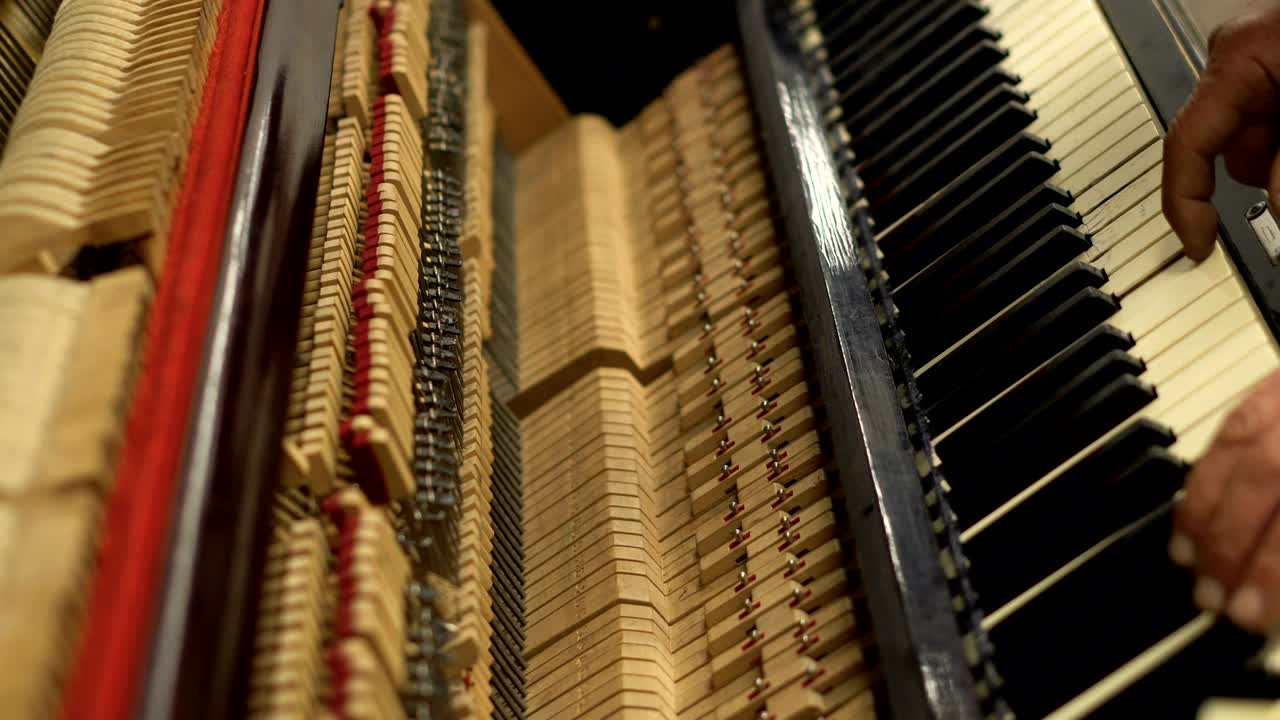 старик в метро играет на пианино с открытым механизмом с струнами и молотками.