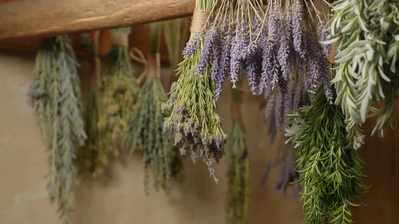 Lavanda ed erbe essiccate appese, luce naturale soffusa che illumina i mazzetti su una ringhiera di legno legati con spago.