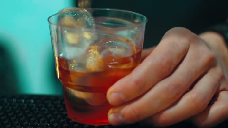 bartender making cocktail with alcohol drink with ice in glass at bar