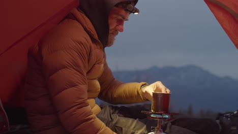 man using portable gas stove in camping tent