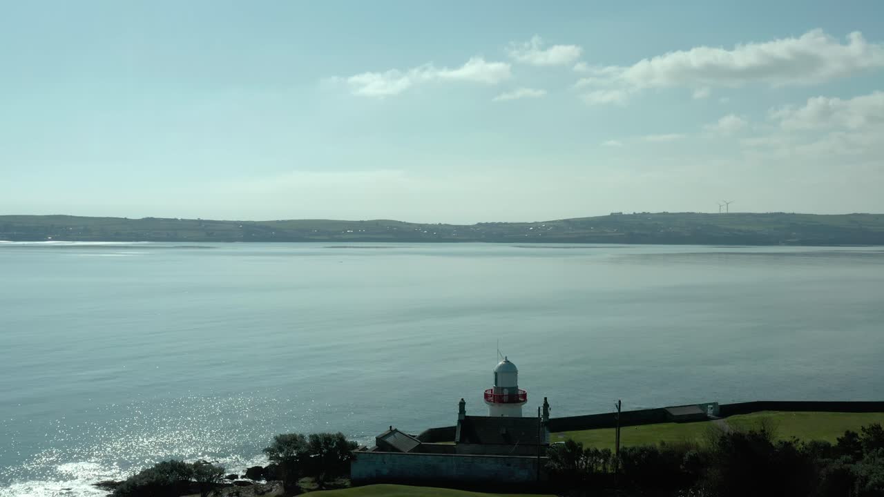 낮에 바다 해안의 등대 위로 날아가는 공중 조감도