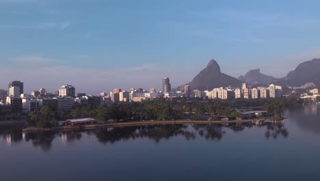 panorámica aérea sobre el lago de la ciudad con isla y club caiçaras en ipanema en primer plano y leblon y la montaña de dos hermanos en el fondo al amanecer temprano