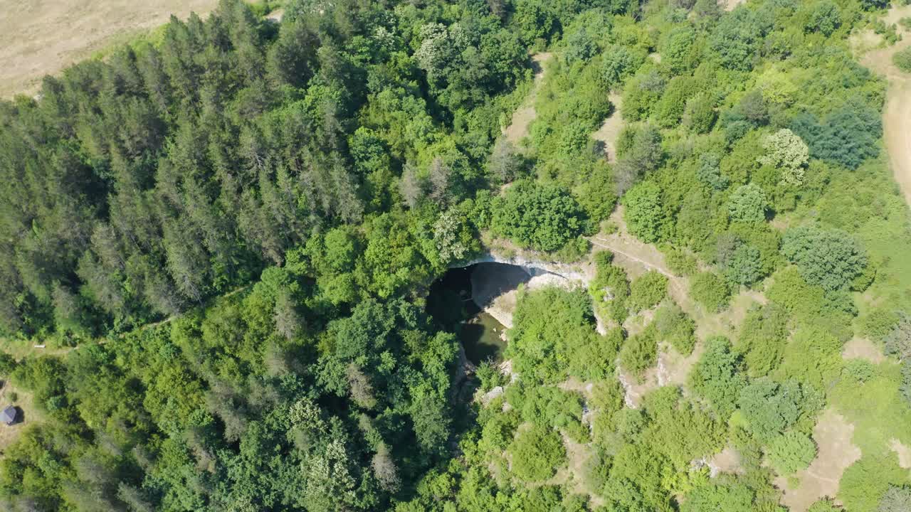 fotografía de un pedestal drone que revela la apertura de la entrada de la cueva, un arco de roca natural llamado puente de los dioses, ubicado cerca de vratsa, en bulgaria