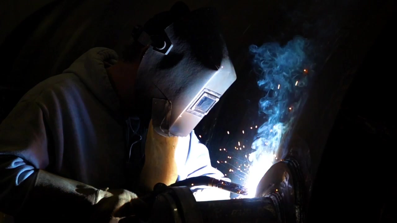 Closeup slow motion shot of a welder with sparks and smoke slowly flying up. 500fps