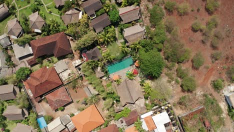 bungalows, villas and swimming pool on bali island indonesia, top down ascending aerial