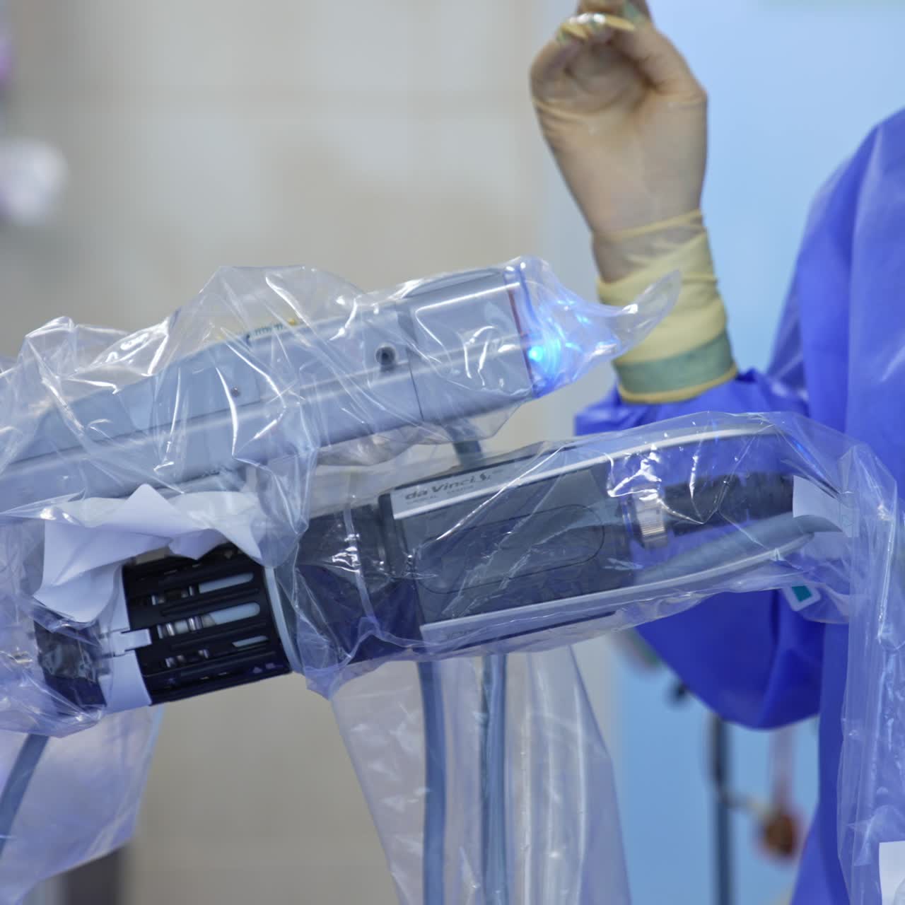 Female first assistant standing at the operative field at the robotic arms. Medic takes a wire and plugs it below the equipment