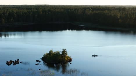 Guy rowing towards small island, coniferous forest, still water (2of2)