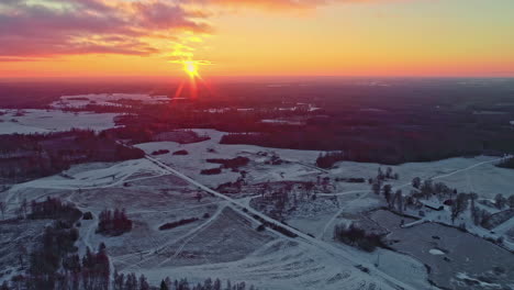 drone volando sobre el paisaje forestal cubierto de nieve con puesta de sol en el horizonte