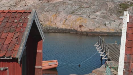 tilt up along rusted corrugated metal and roofing fishing huts with boat moored to wooden pier by lobster pots