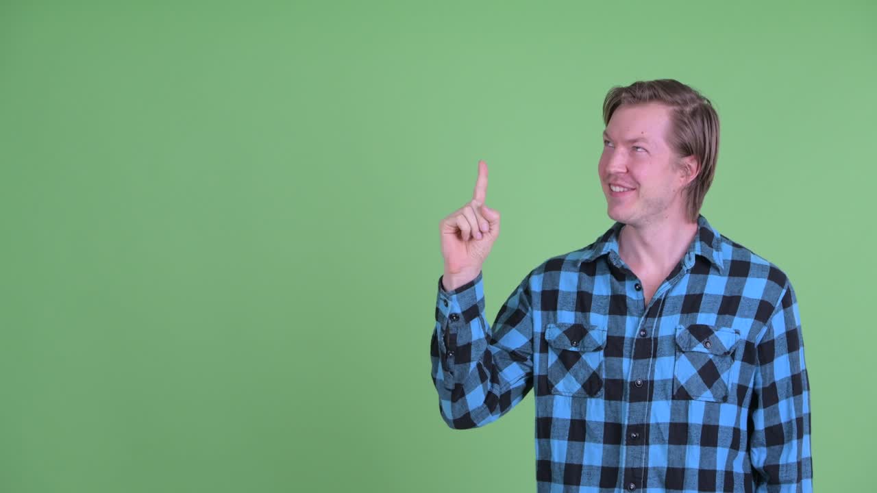 retrato de un hombre caucásico sonriendo y señalando con el dedo para copiar el espacio disparado contra el fondo verde del estudio