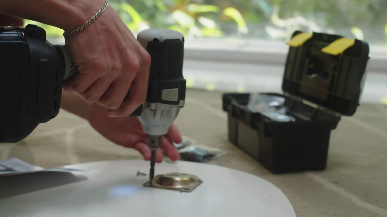 Hands of Man Drilling Metal Fittings on Coffee Table