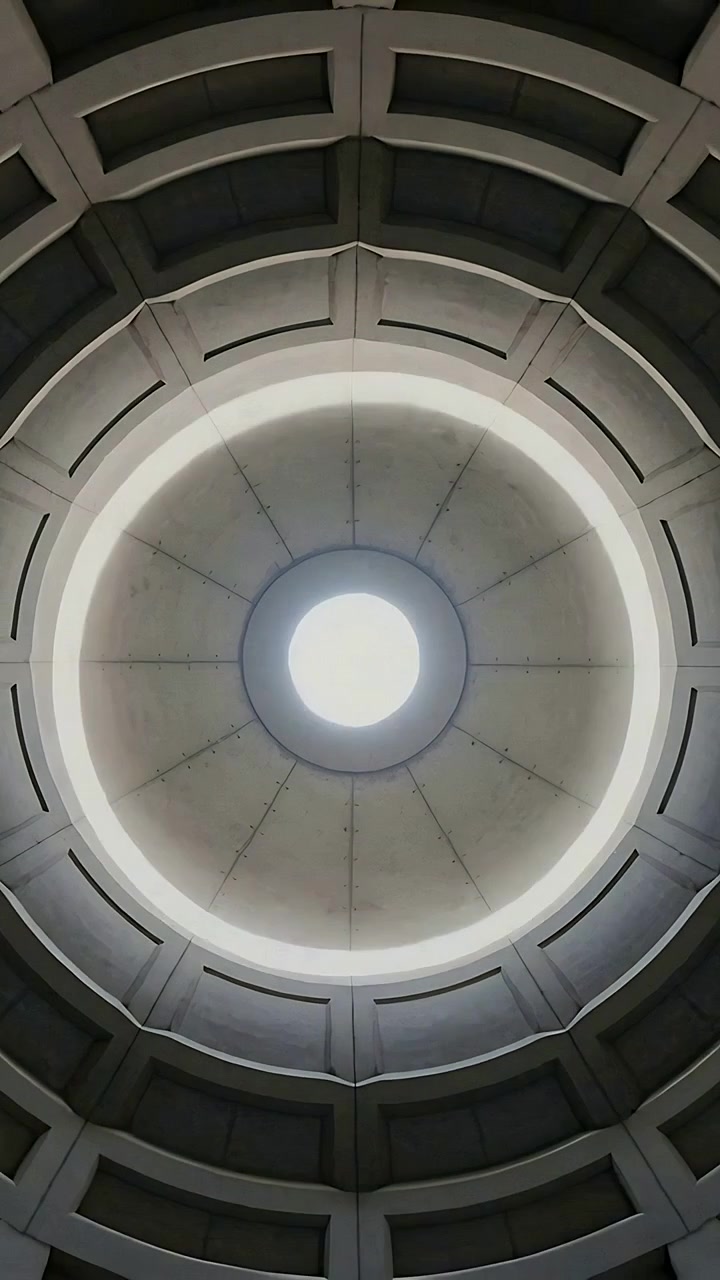 Vertical video: Pulling back camera revealing concrete rotunda dome, exposing oculus, ribs, coffers