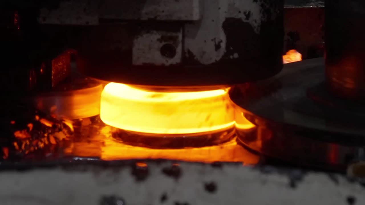 Extreme close-up of a hot ring rolling process where a glowing steel component is shaped by high-pressure rollers and lubricants