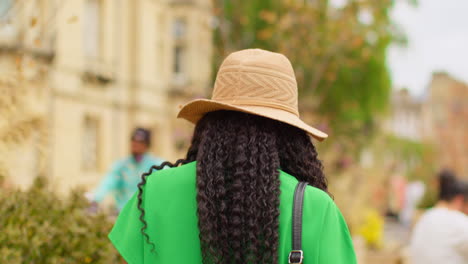 smiling female tourist wearing straw sun hat on vacation in oxford uk exploring city walking along broad street