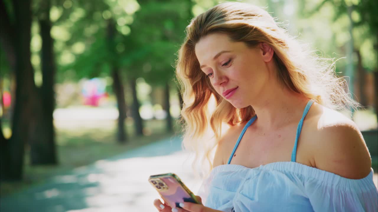 Giovane donna che usa lo smartphone all'aperto in un parco soleggiato