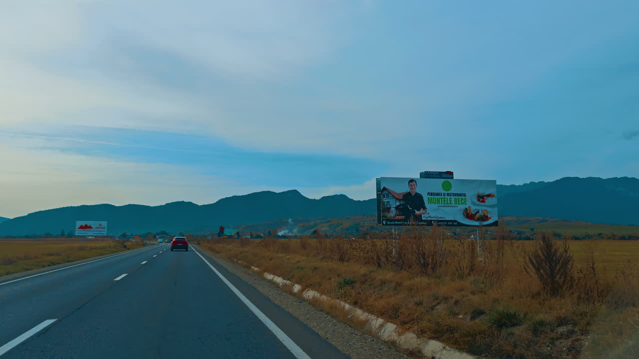 Driving by the speedway through the valley. Silhouette of mountain range at backdrop.