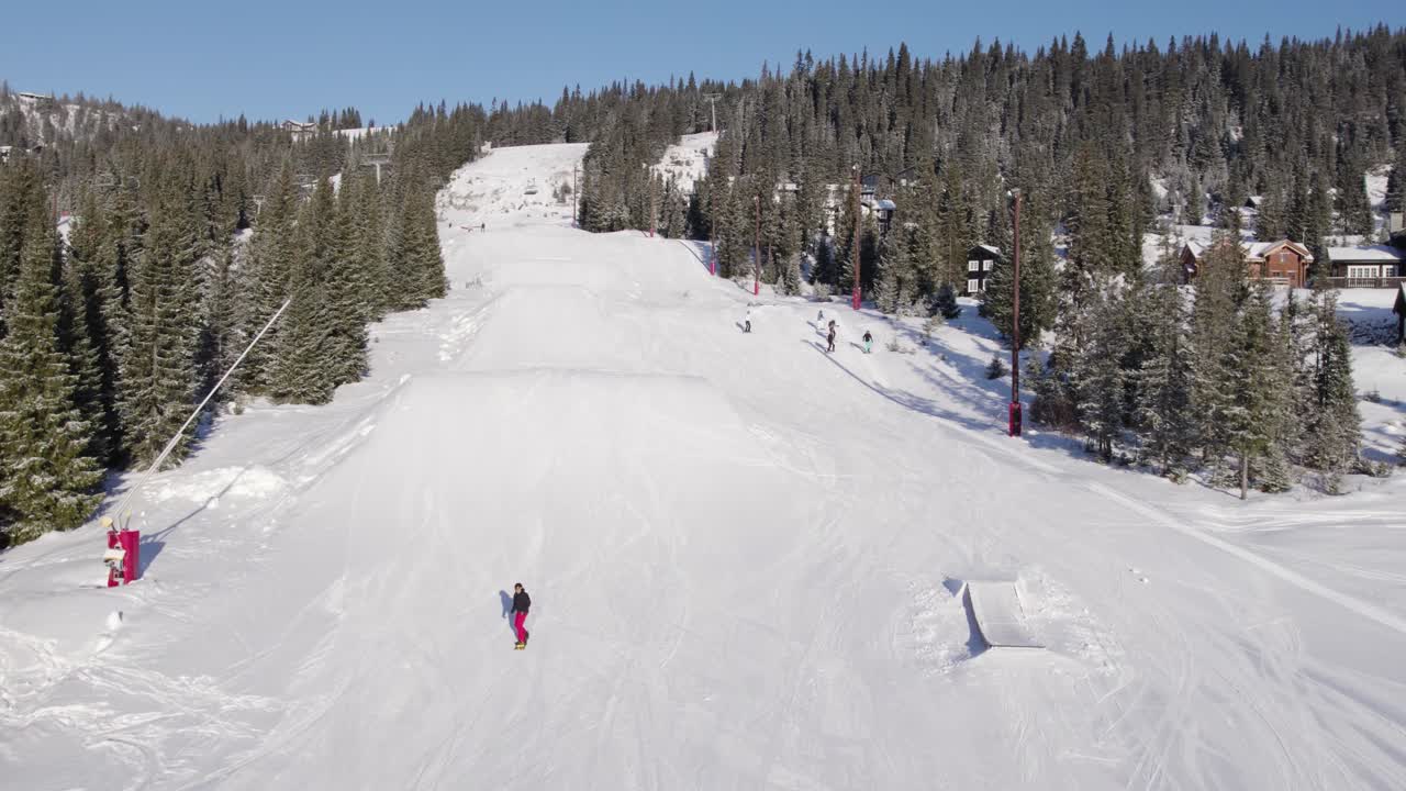 4K aerial drone of snowboarder jumping in the snow on fun park piste on a sunny day in a ski resort in Norway