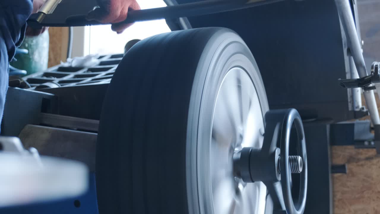 trabajador mecánico hace el equilibrio de la rueda de la computadora en equipos especiales herramienta de máquina en el servicio de reparación de automóviles, foto tonada con efecto de movimiento