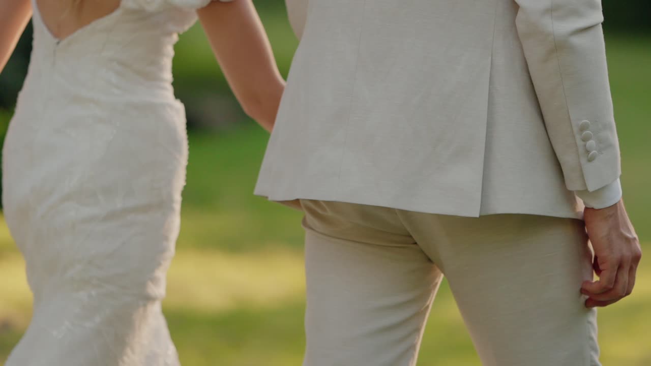 Romantic Couple Holding Hands and Walking in a Park on Their Wedding Day