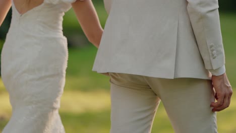 romantic couple holding hands and walking in a park on their wedding day