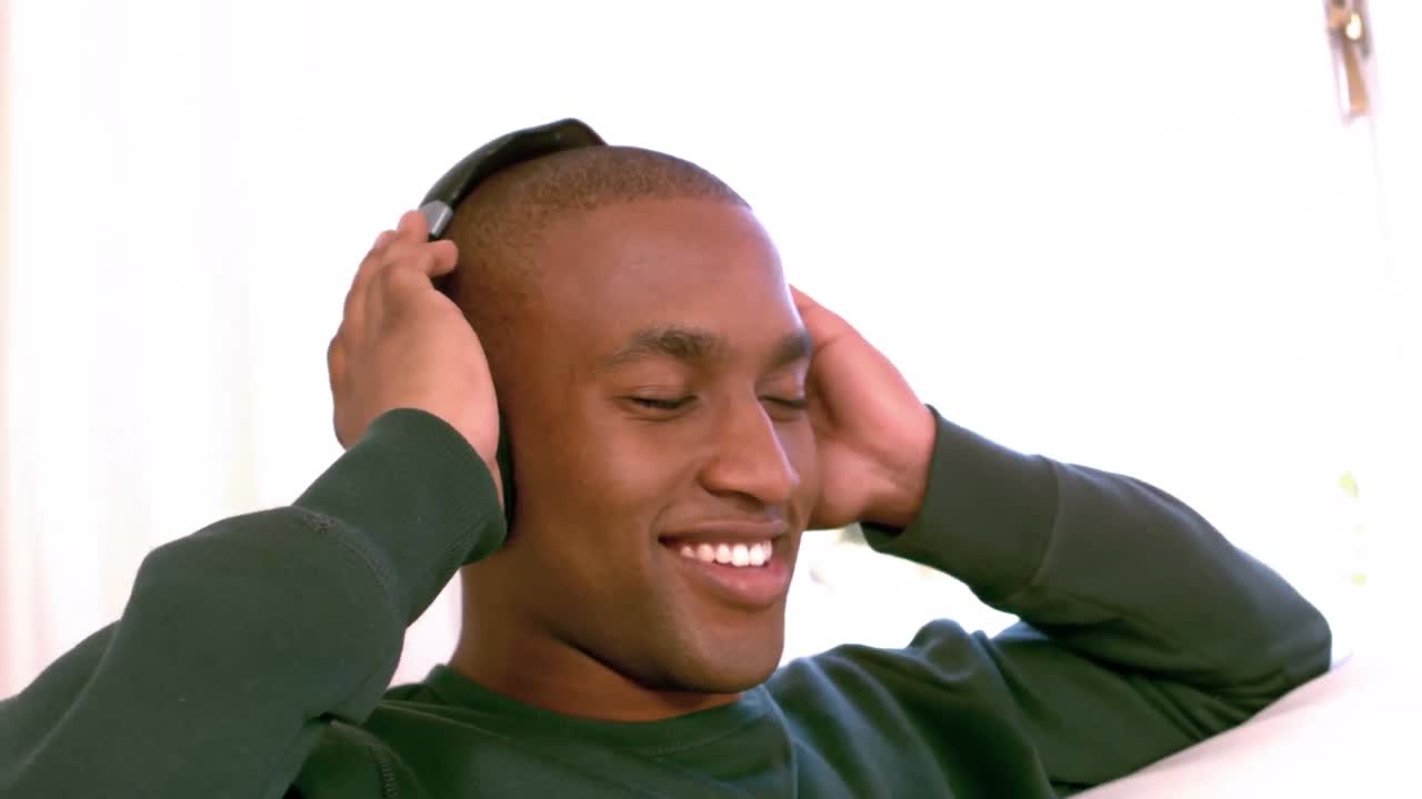 hombre sonriente escuchando música en el sofá