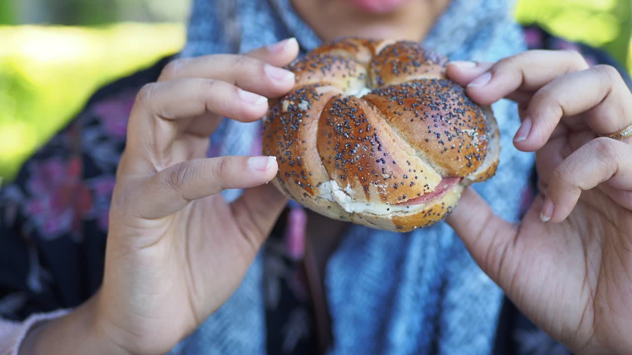 mujer comiendo un sándwich de semilla de amapola al aire libre