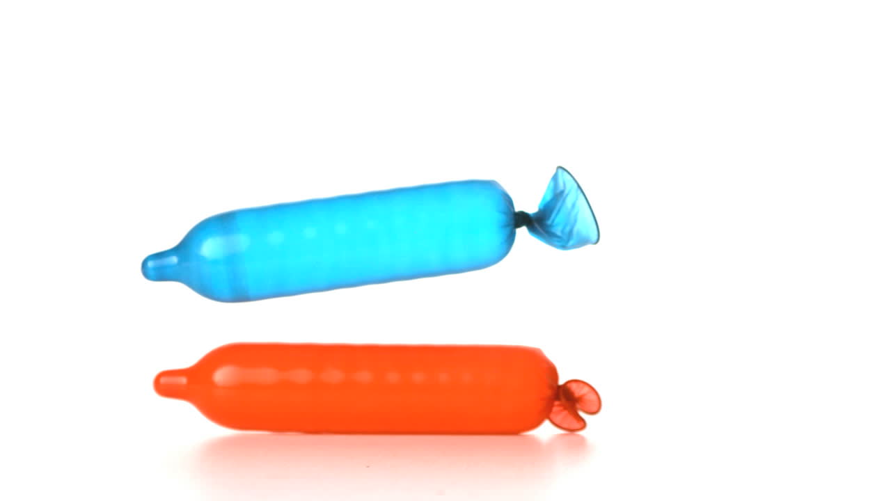 Blown up condom falling on another one on white background